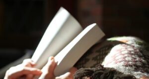 photo of person holding book near textile