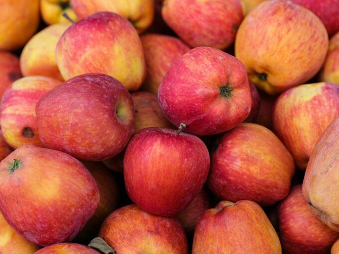 a pile of red apples sitting on top of each other