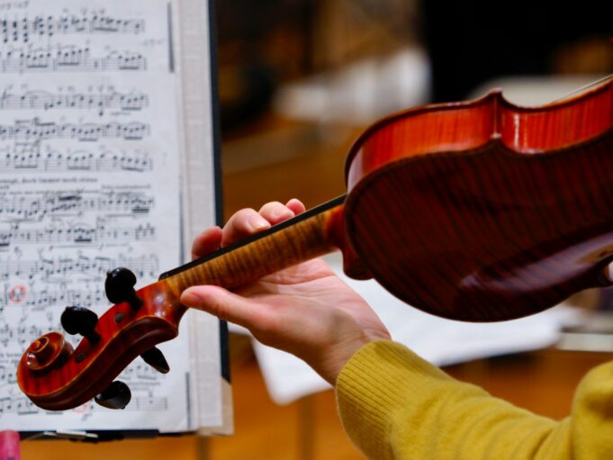 A person holding a violin in front of a sheet of music