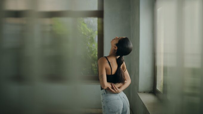 A woman leaning against a wall with her head in her hands