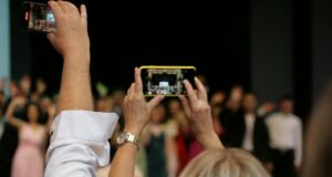 a group of people taking pictures with their cell phones