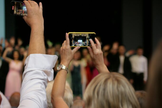 a group of people taking pictures with their cell phones