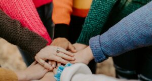 person in red sweater holding babys hand