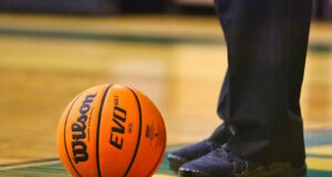 person in black pants and black leather boots standing on basketball court
