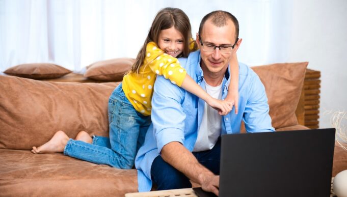 Handsome young man sitting on the couch and working on laptop computer, working remotely from home. Social distancing Self Isolation