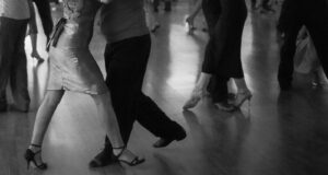 People are dancing on a wooden floor.