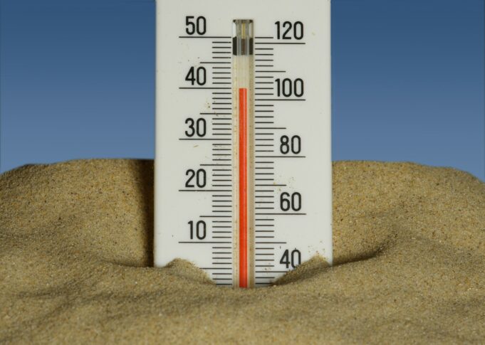 Photo by Immo Wegmann A thermometer in the sand with a blue sky in the background