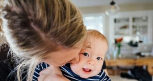woman carrying baby in striped shirt