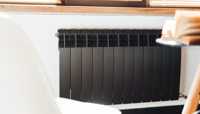 Black aluminum alloy metal heating radiator for home. Black heating battery on the white wall