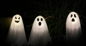 three ghost statues in the dark with their faces glowing