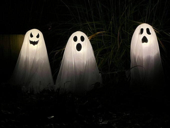 Photo by Jonny Gios three ghost statues in the dark with their faces glowing