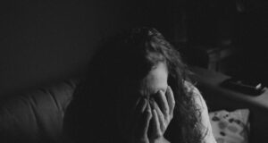 grayscale photo of woman covering face with her hands