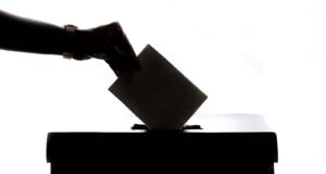 a person is casting a vote into a box