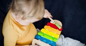 toddler playing wooden xylophone toy