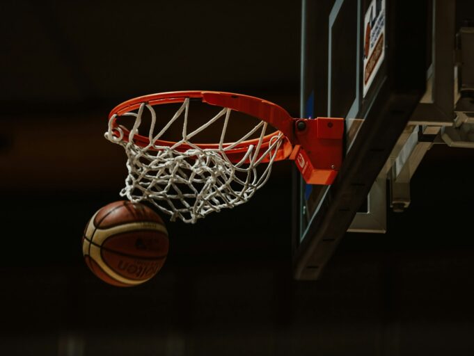 A basketball going through the hoop in a basketball court