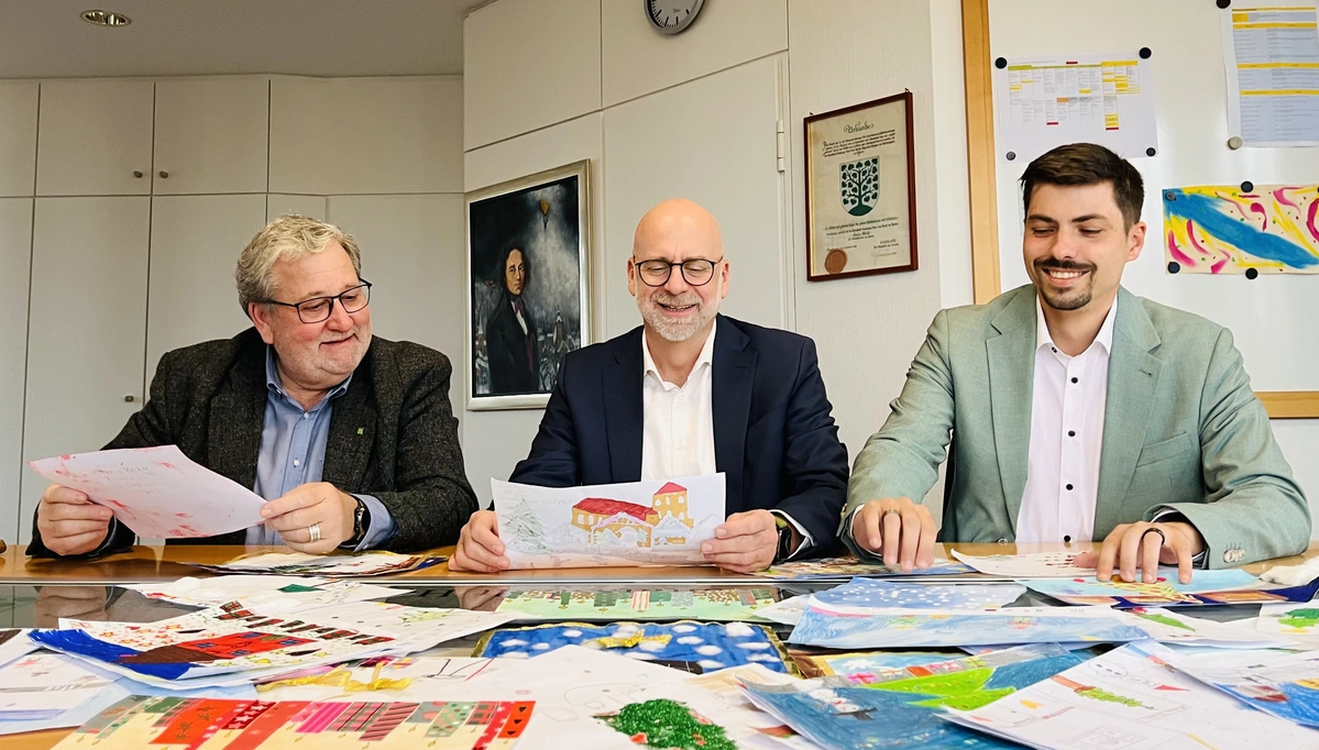 Drei Mitglieder der Jury begutachten eingereichte Weihnachtsbilder.