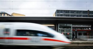a white and red train traveling past a train station