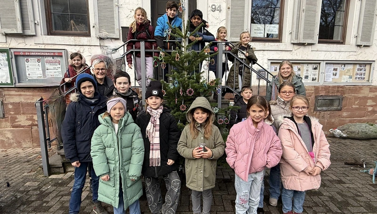 Kinder und Erwachsene stehen vor einem festlich geschmückten Weihnachtsbaum