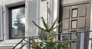 Kinder und Erwachsene stehen vor einem festlich geschmückten Weihnachtsbaum