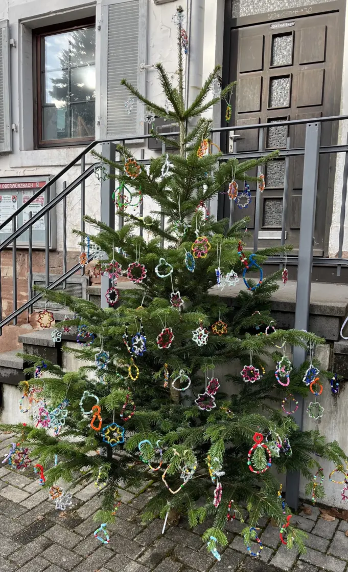 Kinder und Erwachsene stehen vor einem festlich geschmückten Weihnachtsbaum