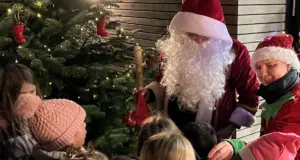 Nikolaus mit Weihnachtswichtel verteilt Geschenke an Kinder