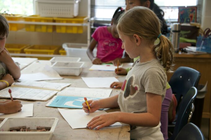 Photo by CDC girl in green crew neck t-shirt writing on white paper